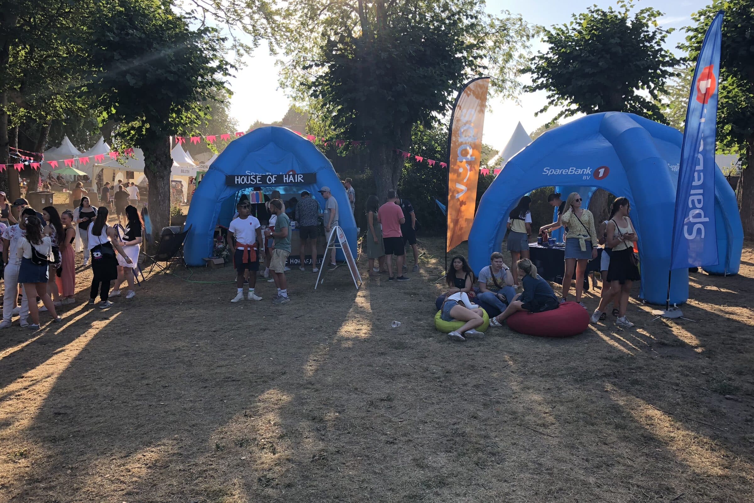Sommerfest utendørs med telt, vimpler og gjester i kveldssol