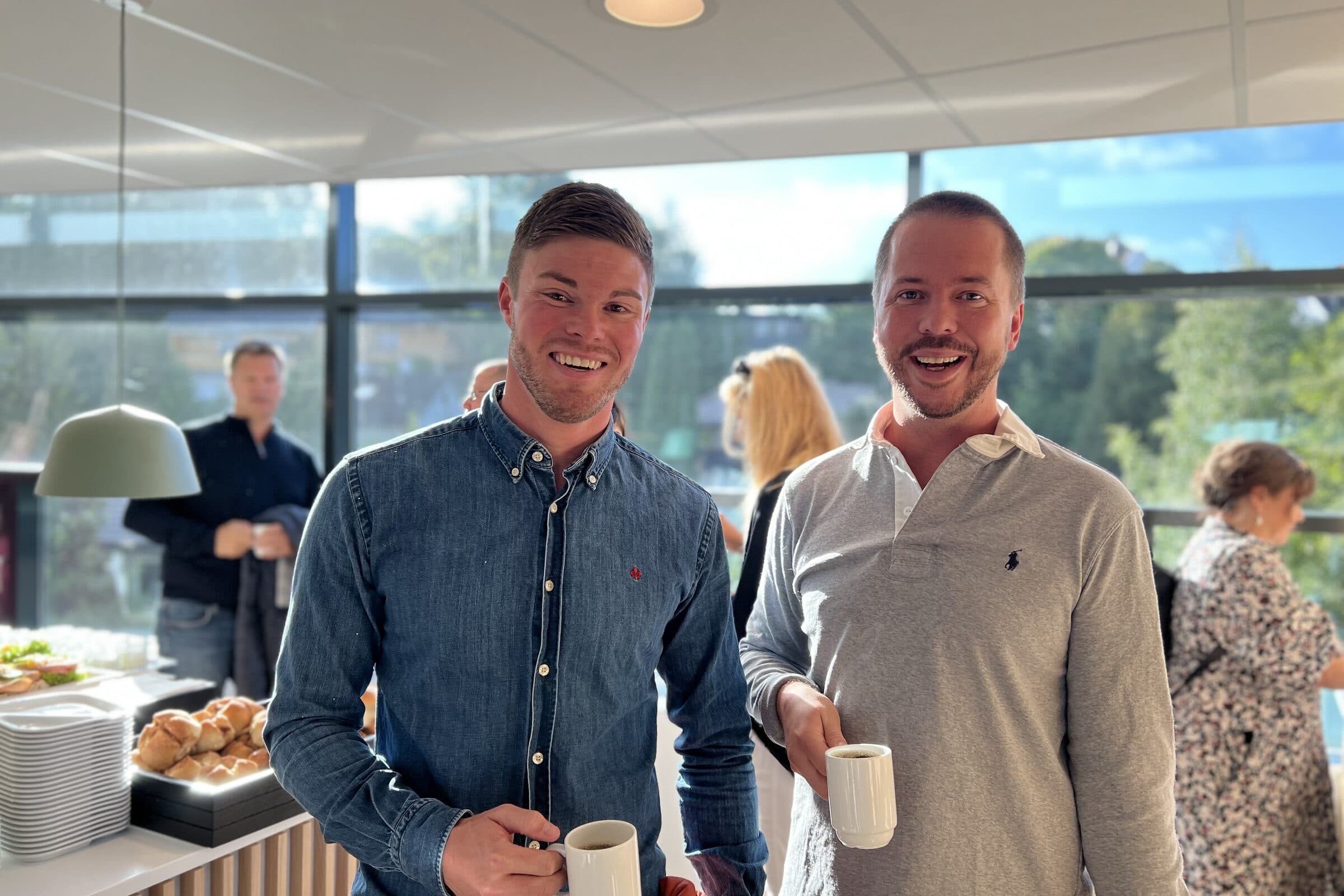 To gjester med kaffekopper ved frokostbuffeten før dagen starter